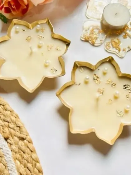 A pair of star-shaped urli candles with gold leaf and pearl embellishments, perfect for festive decor.