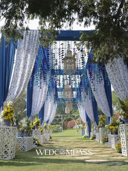 A beautiful walkway decorated with blue and white drapes and hanging floral strings. This entrance creates a dreamy and elegant passage for guests.