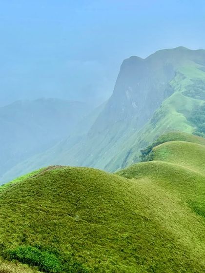 The iconic rolling green hills of a Western Ghats trek, with the path winding its way along the ridge.