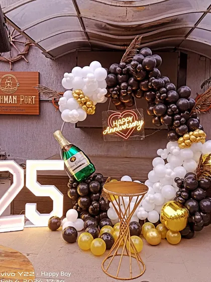 For a sophisticated and modern celebration, I designed this black, white, and gold balloon arch for a 25th anniversary. This setup, complete with a champagne bottle balloon and marquee numbers, is perfect for parties in halls or restaurants.
