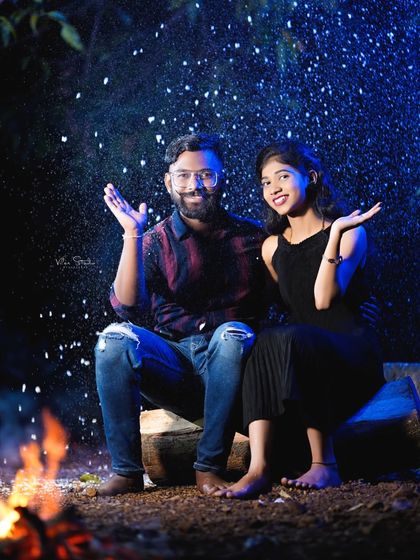 A fun and magical shot with artificial snow falling around the couple. This adds a playful and surprising element to the cozy bonfire theme.