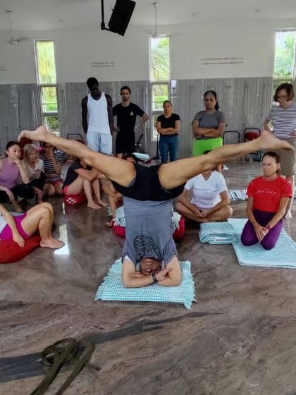 Demonstrating a variation of Sirsasana (Headstand) to students during a yoga festival. The group setting allows for shared learning and observation.
