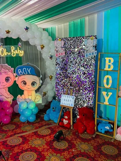 A gender reveal corner at a baby shower, with 'Boy' and 'Girl' marquee letters and teddy bears in blue and pink.