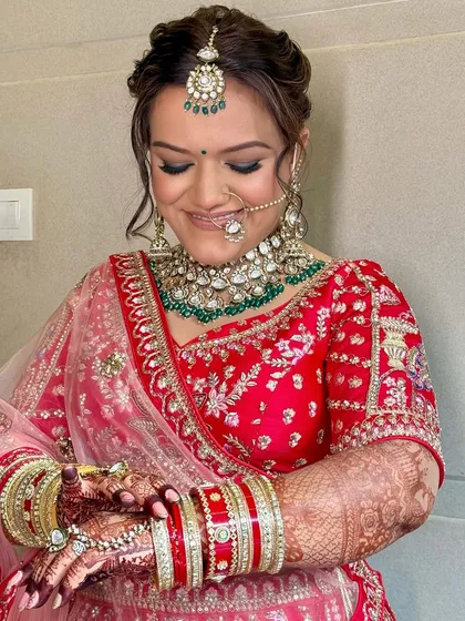 A beautiful candid moment of the bride, her smile as radiant as her makeup. The soft smokey eyes and glowing skin are perfect for a classic red bridal lehenga.