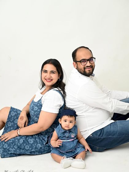 A fun and unique family pose. Sitting back-to-back, the parents create a lovely frame for their adorable daughter sitting in the middle.