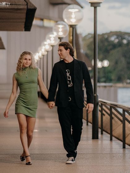 A simple, romantic shot of the couple walking hand-in-hand along a promenade in Sydney. The warm lighting and their connected gaze make for a timeless and natural portrait.