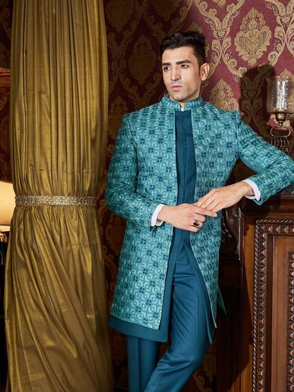 The rich color and intricate pattern of this teal ensemble are perfect for a Sangeet or reception. The bespoke fit ensures a sharp and flattering silhouette.