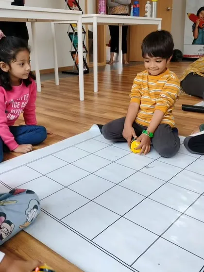 More screen-free fun at our Whitefield center, as young children work together to program the Bee-Bot on a large floor mat.