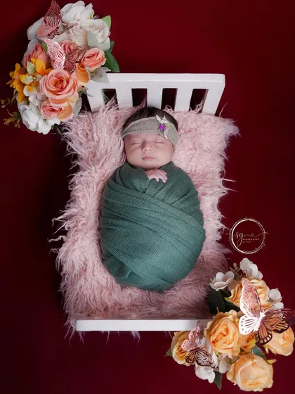 Another angle of the newborn in a miniature crib, adorned with flowers and butterflies, creating a magical and serene portrait.