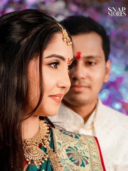 A close-up profile of the bride in her traditional attire, with the groom in the background. This artistic shot focuses on the bride's beauty and intricate jewelry.