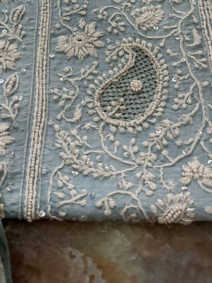 A macro shot of a single paisley motif, highlighting the 'jaali' work within.