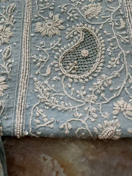 A macro shot of a single paisley motif, highlighting the 'jaali' work within.