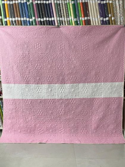 The back of the quilt, featuring a simple design in pink and white.