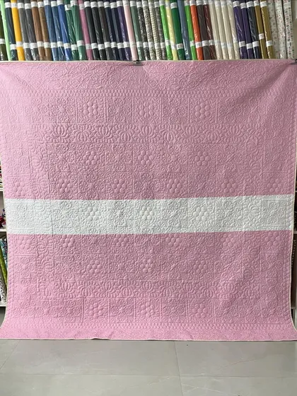 The back of the quilt, featuring a simple design in pink and white.