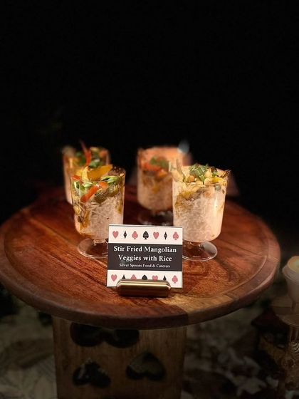 A moody, atmospheric shot of the Stir Fried Mongolian Veggies with Rice. The dark background and focused lighting emphasize the dish and its thematic card-suit label.