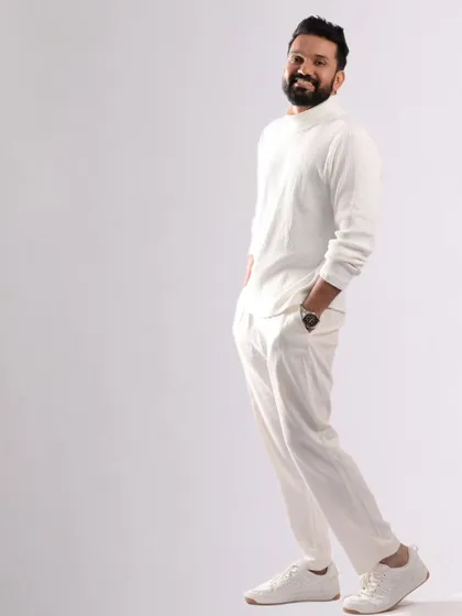 A full-length shot showing the complete all-white look. The grooming contributes to the clean, crisp, and modern aesthetic of the photo.