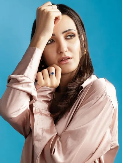 A close-up from the satin and denim series, focusing on the model's expression and the contrast between the soft shirt and the bold blue background.