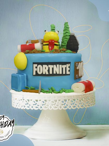 A fun Fortnite cake for a 10th birthday. This design features characters and items from the game, ready to drop into the celebration.