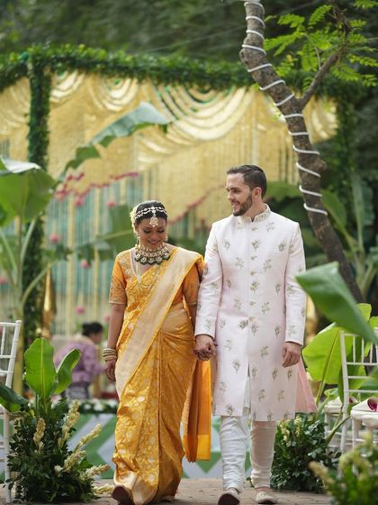A beautiful moment from a traditional South Indian wedding I designed. The bride's rich Kanjeevaram silk saree and the groom's elegant sherwani are perfectly complemented by the lush, natural decor of the mandap in the background.