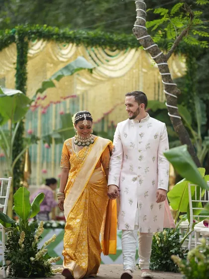 The walk down the aisle at a fusion wedding is a powerful symbol of two paths becoming one. I ensure the decor, like this lush green walkway framed by banana plants, complements the couple's attire and the blend of traditions.