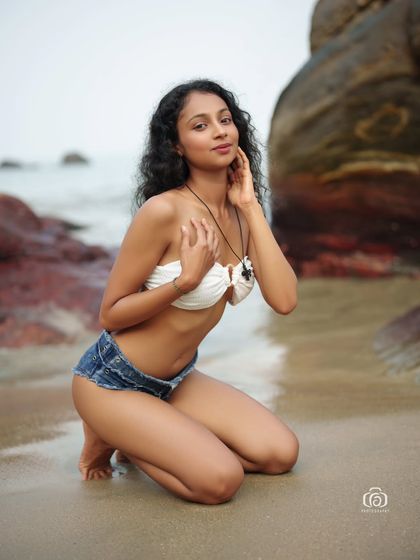A kneeling pose on the wet sand, with the waves gently washing in. This shot captures a serene and intimate moment on the beach.