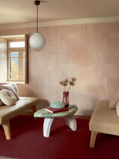 Our wallcoverings go beyond simple aesthetics, offering a unique blend of texture and color. Here, a soft, rosy-hued wallpaper with a subtle sheen creates a warm and inviting backdrop that elevates the entire room.