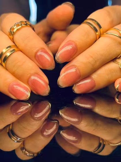 A beautiful and simple manicure with a sheer, shimmery pink polish and a delicate gold outline at the tip.