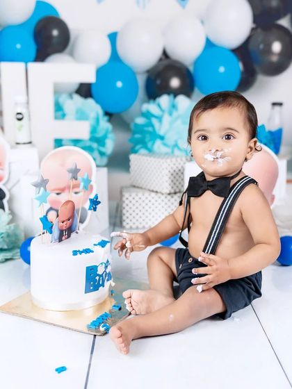 A happy baby boy with cake on his face, enjoying every moment of his first birthday cake smash.