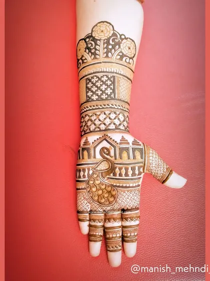 This design features a peacock on the palm, with its feathers flowing up the arm. The intricate details in the peacock and the surrounding patterns showcase a high level of artistry.