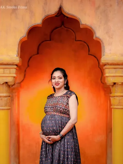 A lovely solo portrait of the mom-to-be in a modern printed gown. The warm, vibrant background and her happy expression make for a beautiful and contemporary maternity photo.