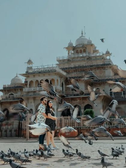 A dynamic shot of a couple at Albert Hall Museum in Jaipur, surrounded by a flurry of pigeons. This image is full of life and movement, capturing a spontaneous and joyful moment.