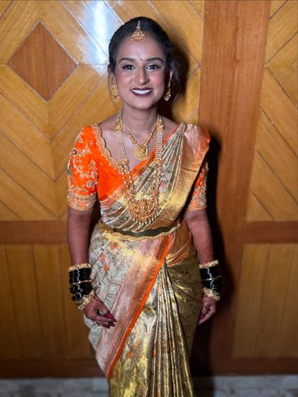 The perfect bridal smile. This bride's radiant happiness is the final touch to her traditional South Indian wedding look, complete with temple jewellery and a vibrant orange Kanjeevaram saree.