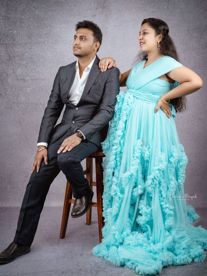 A stylish couple pose. The partner's sharp suit complements the flowing sky-blue gown for a modern and fashionable maternity photo.