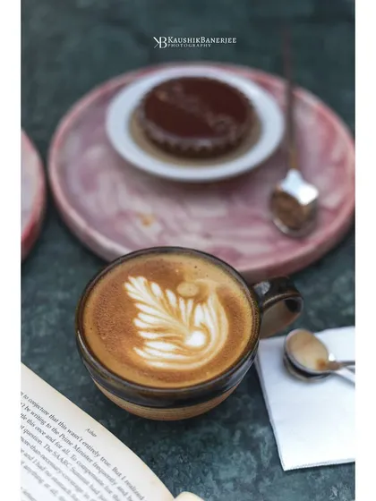 A cappuccino with perfect latte art, seen from a personal, intimate angle. This shot captures the cozy, comforting culture of a coffee shop, ideal for cafe menus and social media.