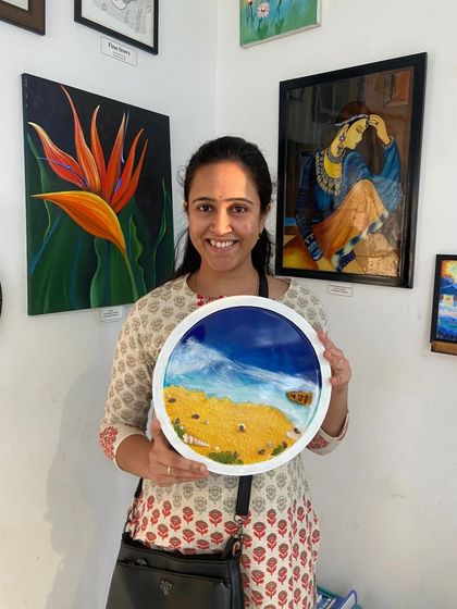A participant proudly holds up her finished resin beach art. The vibrant colors and glossy finish are hallmarks of this popular workshop.