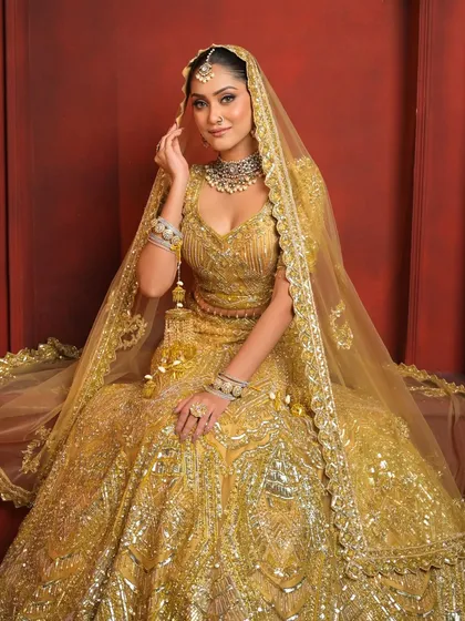 A majestic seated portrait, showcasing the full grandeur of the golden lehenga. This look is a statement of luxury and style.