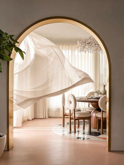 A shot of the dining area through the arches, with a sheer curtain caught in motion, adding a touch of ethereal beauty.