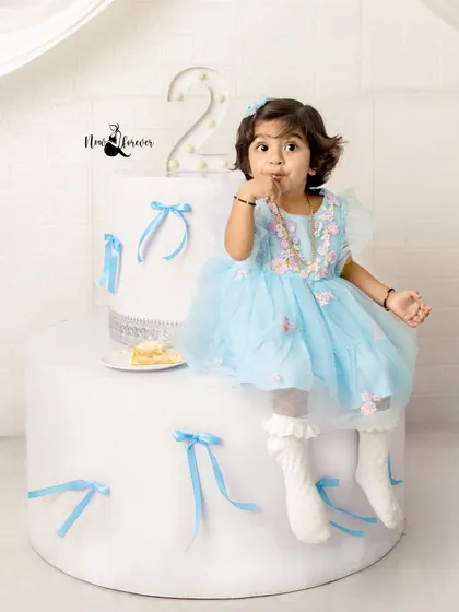 Enjoying a little piece of cake while sitting on her giant birthday prop. This is a sweet and stylish way to celebrate turning two.