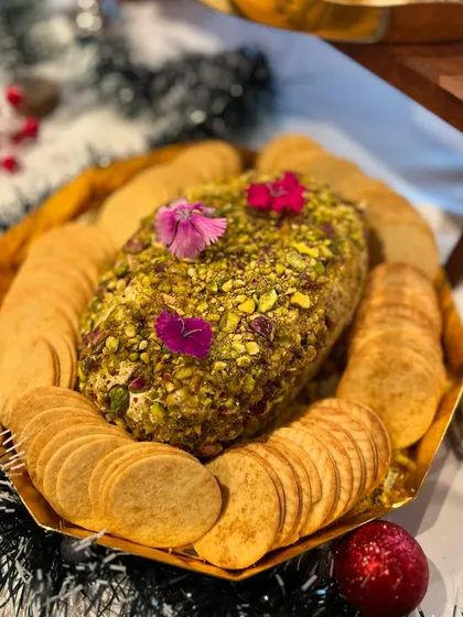A pistachio-crusted cheese log, a centerpiece for a Christmas-themed high tea. It's a savoury and festive addition to any holiday spread.