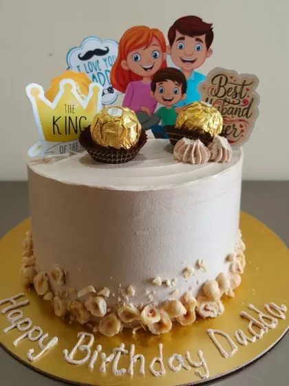 A sweet family themed cake for a dad's birthday, topped with Ferrero Rocher and hazelnuts.