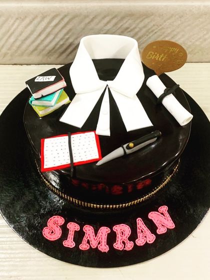 A sleek and professional cake for a lawyer. This all-black cake is topped with a fondant advocate's band, law books, and a graduation scroll.