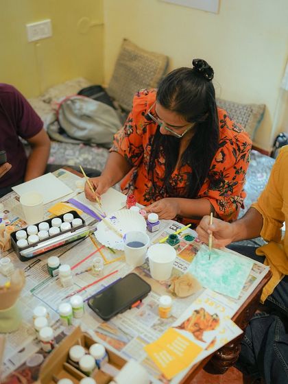 A participant gets creative at our "Paint with Kittens" event, with all the art supplies spread out on the table.