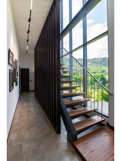 This is a duplicate of ID 72. A minimalist staircase with wooden treads runs alongside a double-height window.