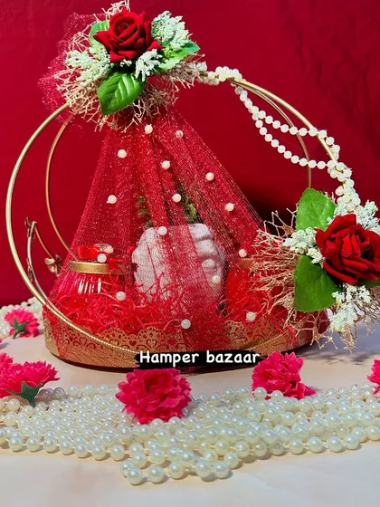 This stunning red and gold hamper is perfect for making a statement. The metal ring basket is decorated with net, pearls, and roses, creating a luxurious look for your Diwali gifts.