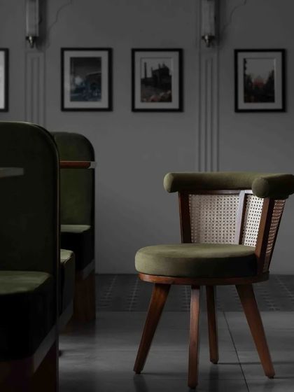 This custom chair combines a teak frame with green velvet upholstery and a woven cane backrest, showcasing our expertise in bespoke furniture design for commercial projects.