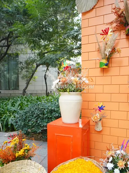 Decor details at the entrance, featuring baskets of marigold petals and floral arrangements on orange pedestals.