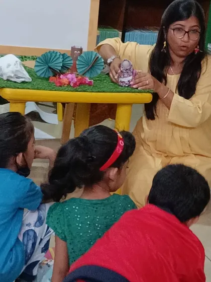 Children gather around the activity table, excited to interact with the story props.