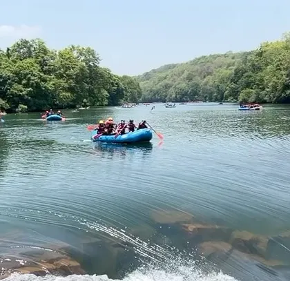 A wide view of the Kali River with multiple rafts and kayaks, illustrating the scale of our summer camp activities in Dandeli.
