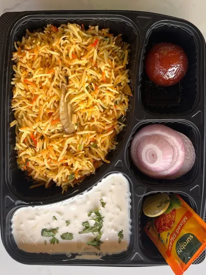 A delicious and convenient biryani meal box. This option includes fragrant vegetable biryani, creamy raita, a gulab jamun, and a side of pickled onions, making it a perfect single-serving meal for lunch meetings or events.