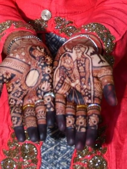 A close up view of a bridal portrait, showing the bride and groom together in a single, intricate design on the palm.